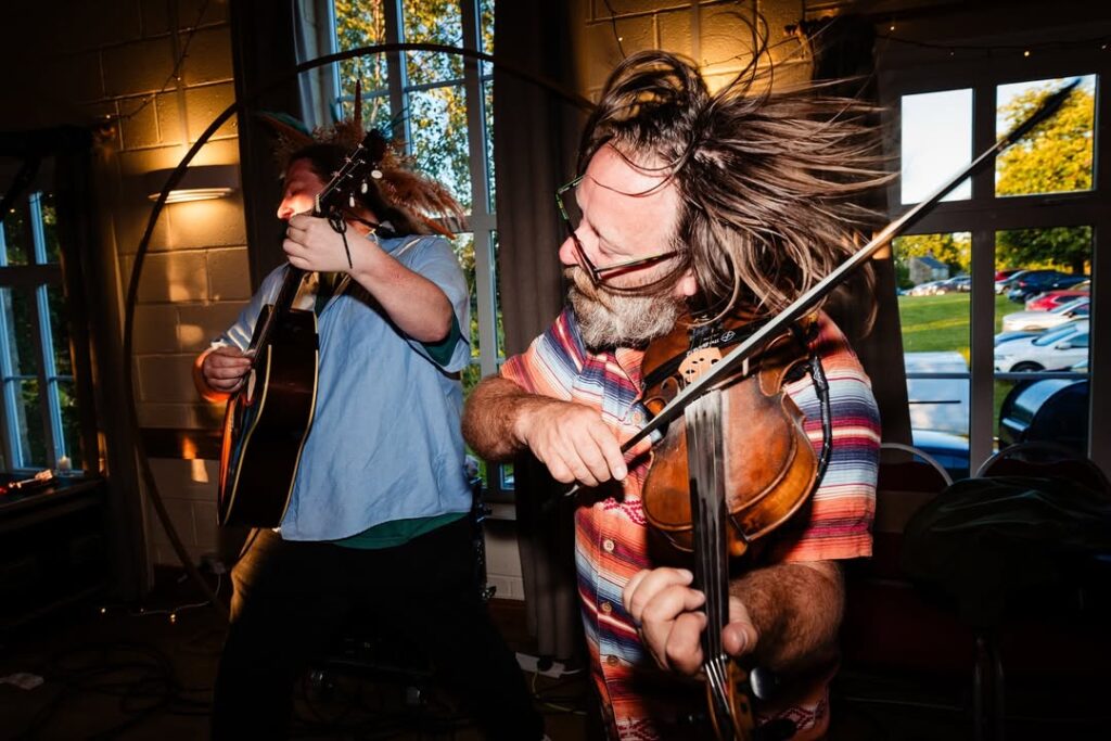 Fiddle player and guitarist playing flat out, hair flying, at an evening gig