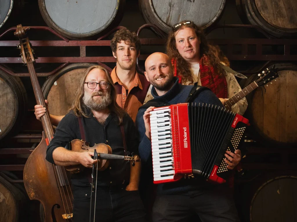 Hyde Family Jam with double bass, fiddle, accordion and guitar in front of a wall of barrels
