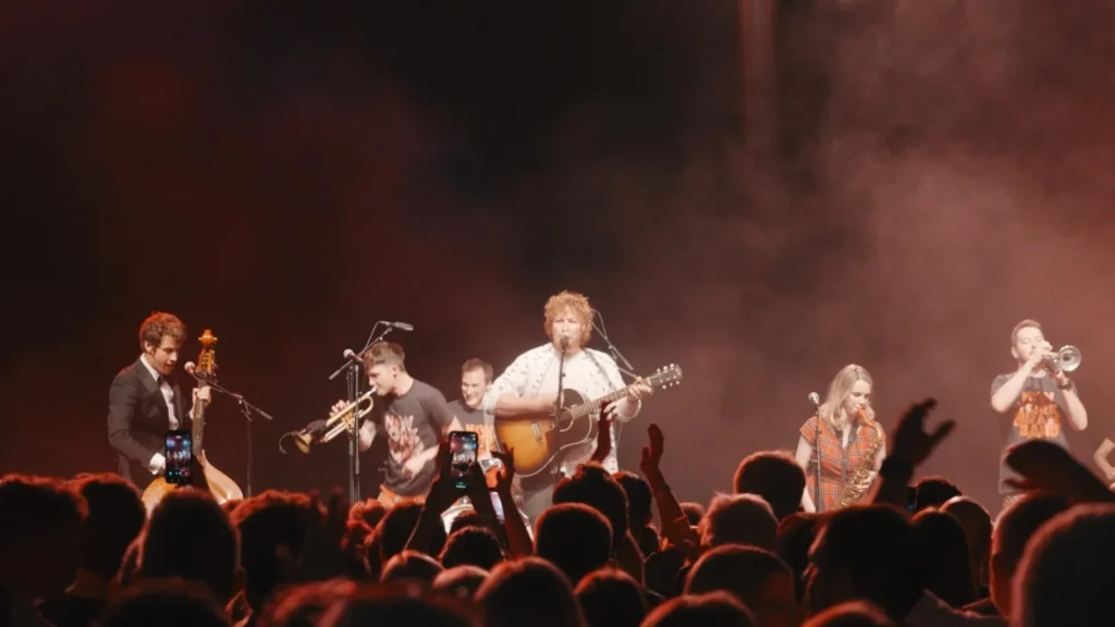 The band with a brass section on a smoky red-lit stage