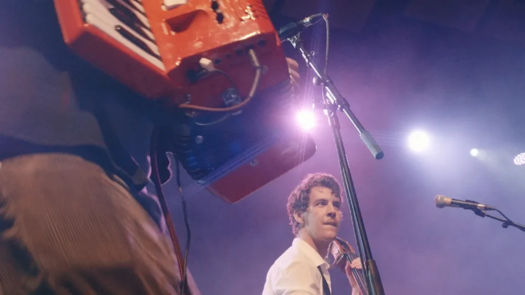 Double bassist looking up past the red accordion, seen from below