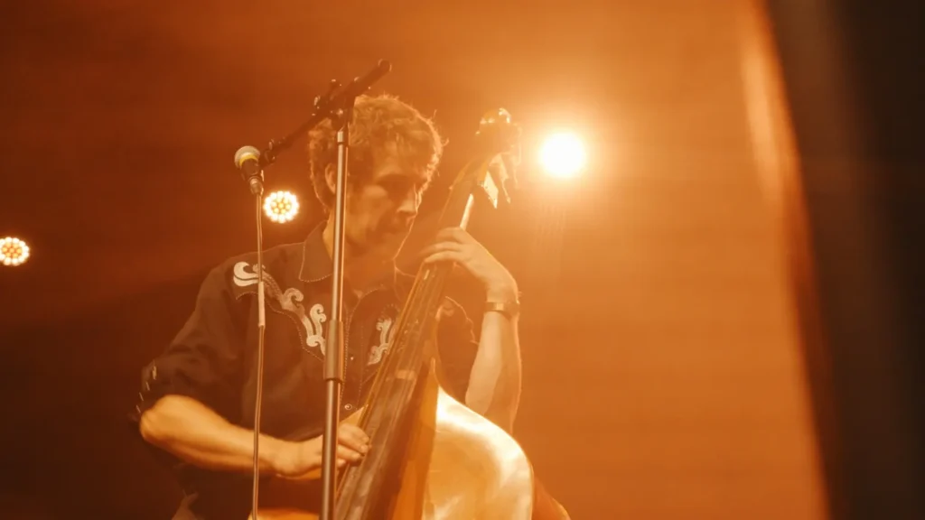 Double bassist playing under warm orange stage lights