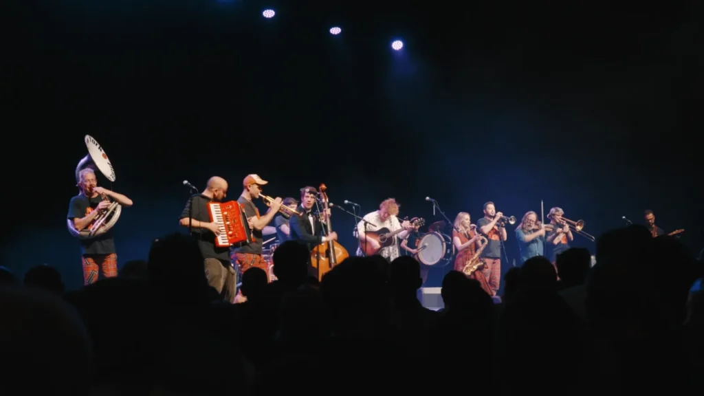 The band and brass section playing across a dark stage