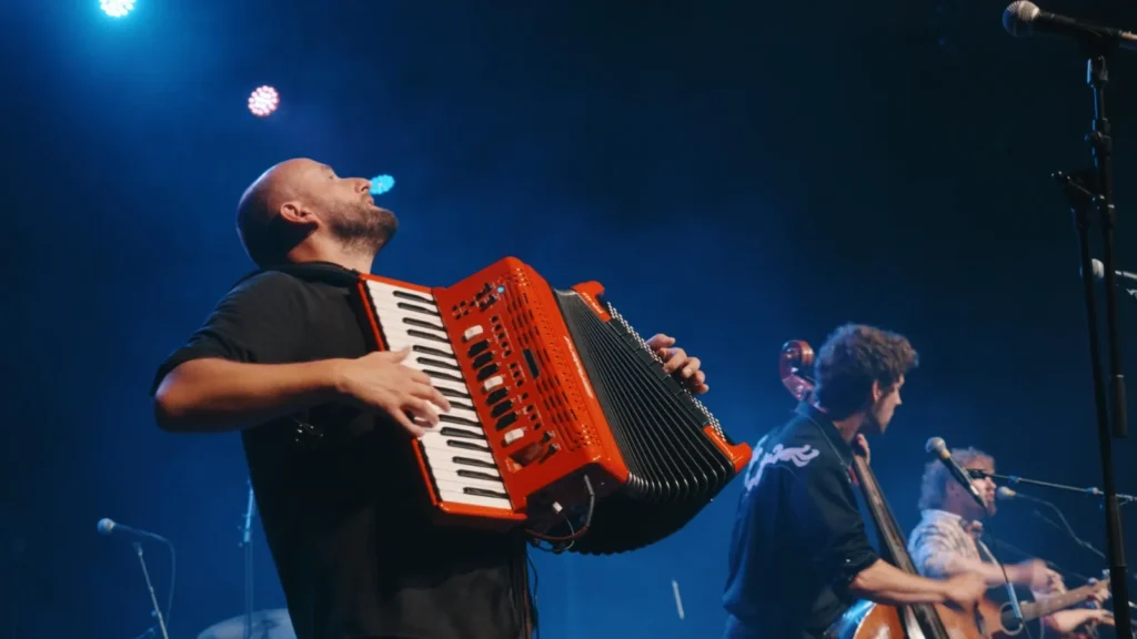 Accordion player leaning back mid-song, with the bassist and guitarist behind