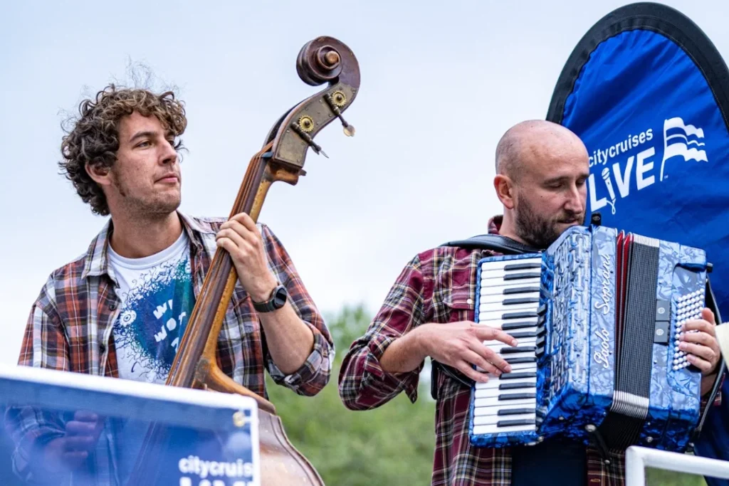 Two of the band playing double bass and accordion on a City Cruises boat